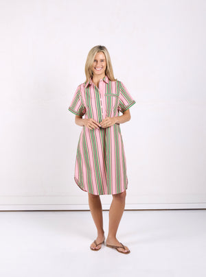 A woman modeling a short-sleeve button-up shirt dress with vertical pink, green, and white stripes, standing against a plain white studio background.