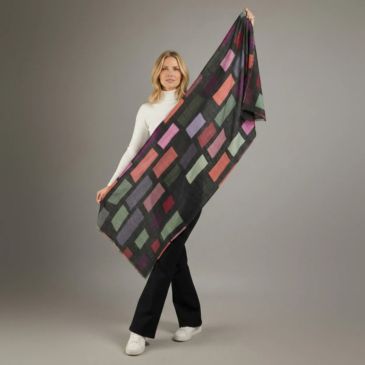 Woman holding a colorful patterned blanket against a gray background
