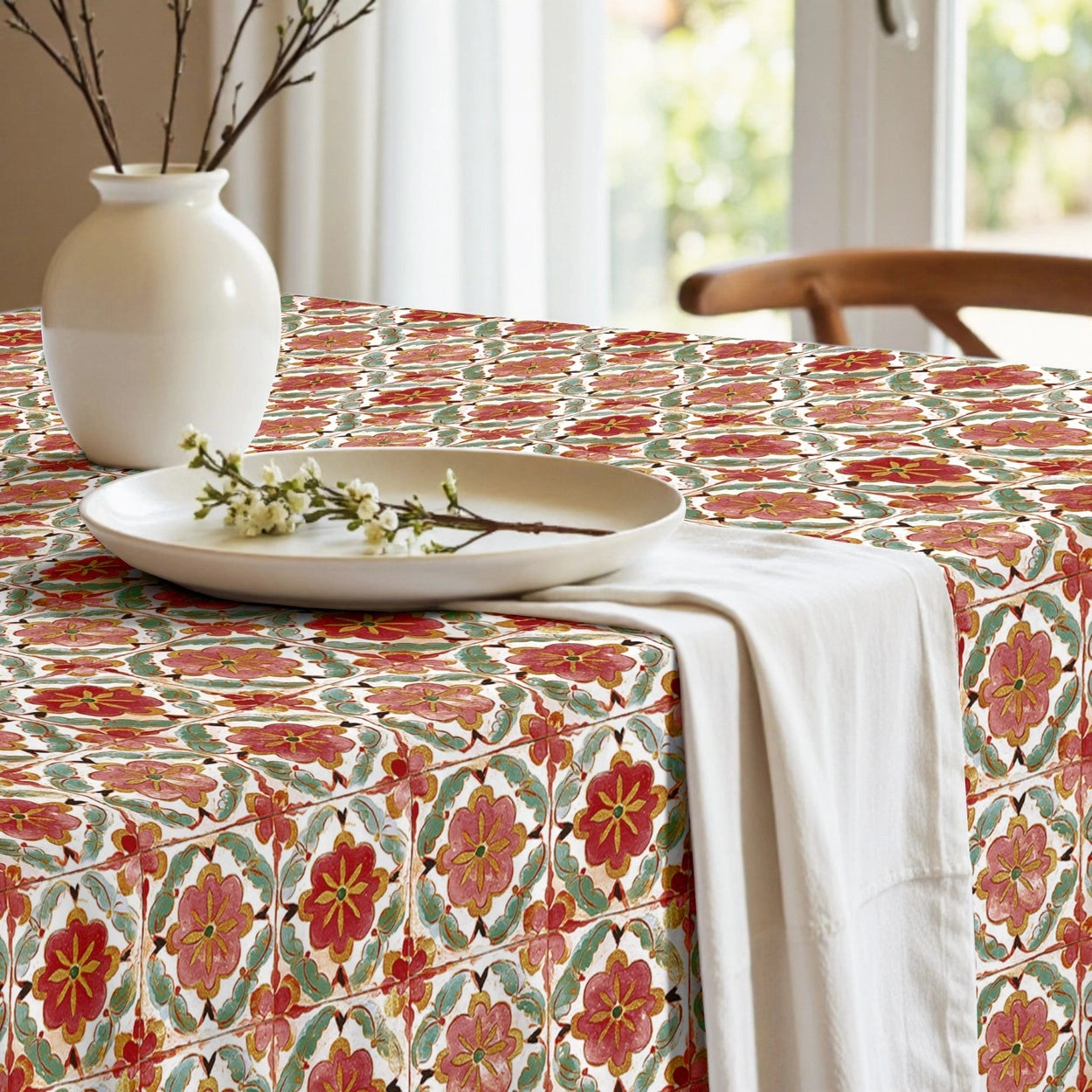 Tablecloth with a red and white pattern on a table in a bright room with large windows.