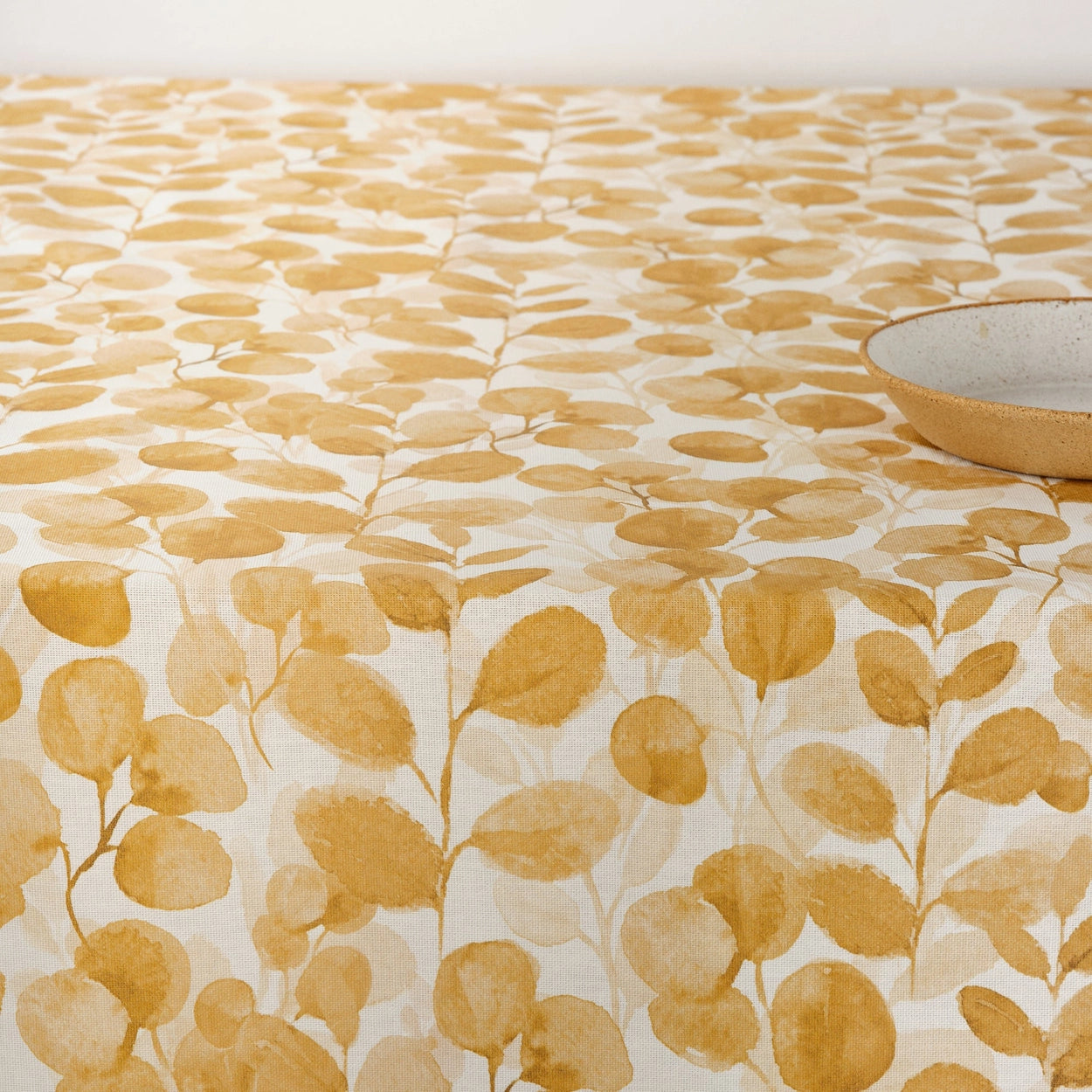 Table with a yellow leaf patterned tablecloth on a white background