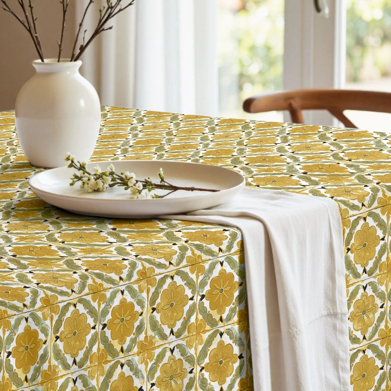 Tablecloth with yellow geometric pattern on a wooden table in a bright room with large windows.