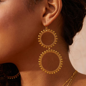 Gold hoop earrings worn by a person with a neutral background