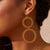 Gold hoop earrings worn by a person with a neutral background