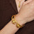 Gold bracelets on a wrist against a brown background