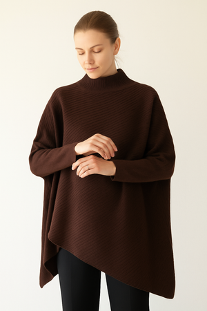 Woman wearing a brown poncho style jumper against a white background