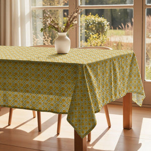 Tablecloth with yellow geometric pattern on a wooden table in a bright room with large windows.