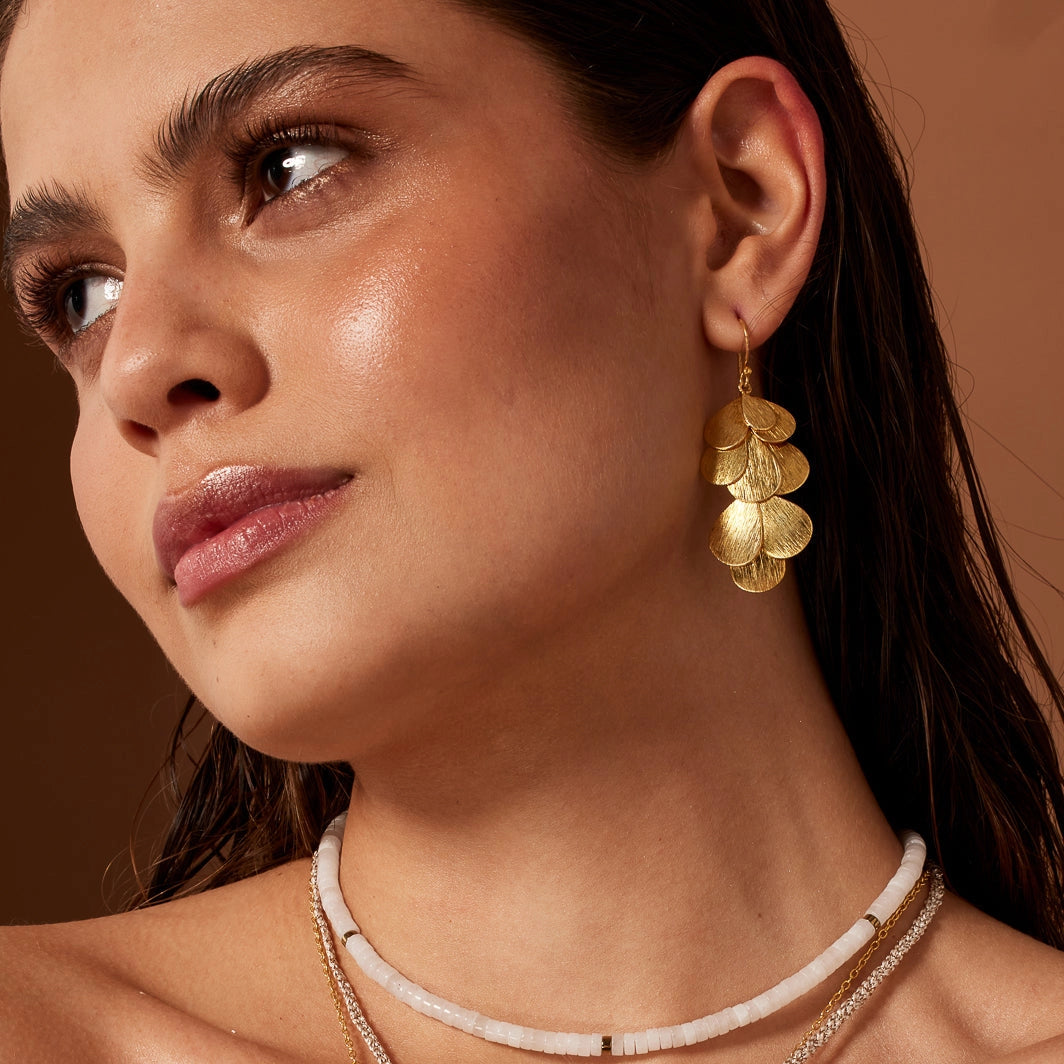 Gold leaf-like earrings on a white background