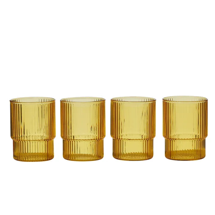 Four amber-colored glass tumblers with ribbed design on a white background