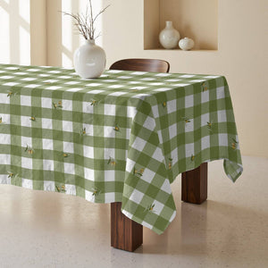 Green and white checkered tablecloth on a wooden table with decorative vases in the background.