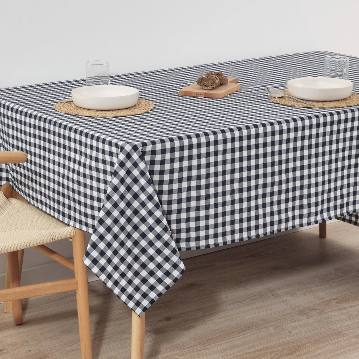 Table with a navy and white checkered tablecloth, wooden chairs, and minimal decor.