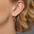 Gold earring with a purple gemstone worn by a person with blonde hair.