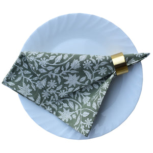 Floral-patterned napkin on a white plate with a gold napkin ring.