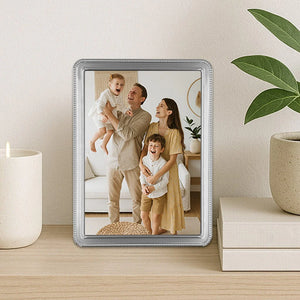 Framed family photo on a table with a plant and candle in the background