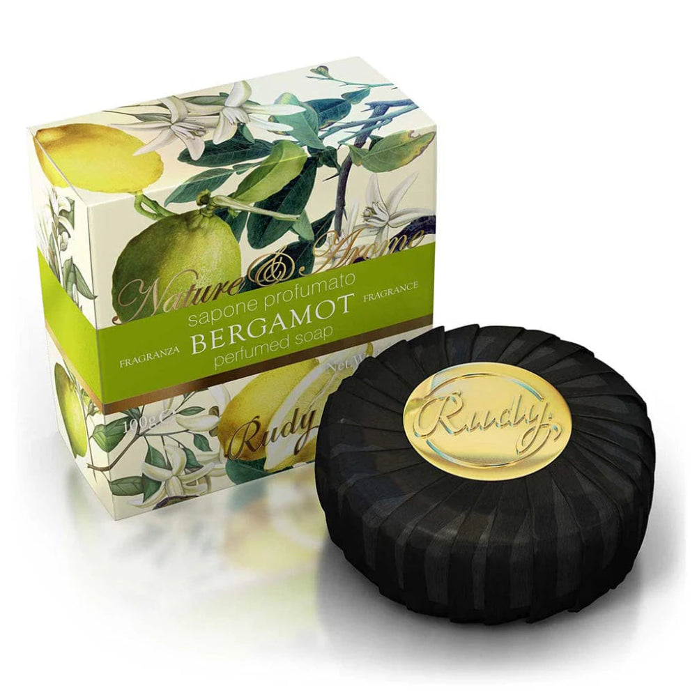 Black soap bar with gold label next to a decorative box featuring lemons and leaves on a white background