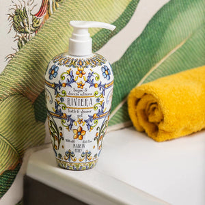 Decorative bath and shower gel bottle with floral patterns on a white surface with a yellow towel and green fabric.