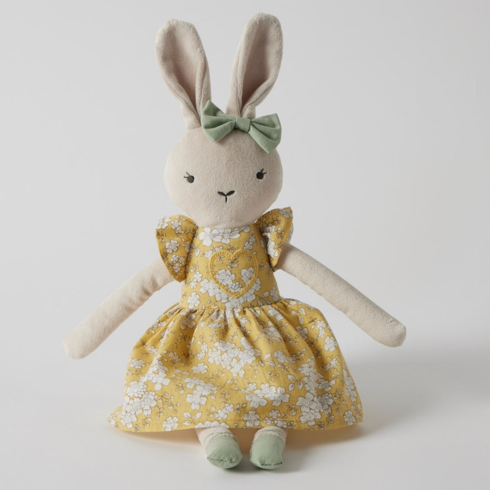 Stuffed bunny toy in a yellow dress with a green bow on a white background