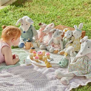 Child playing with plush toys on a blanket outdoors