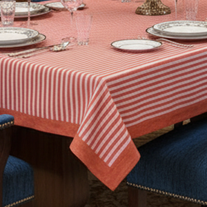 Table setting with a red and pink striped tablecloth, plates, and glasses.