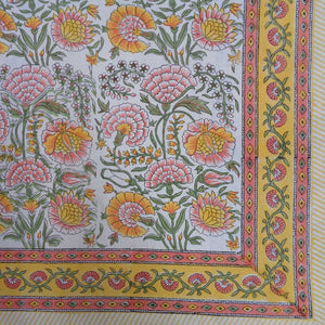 Colorful floral patterned fabric with pink, yellow, and green flowers on a white background.