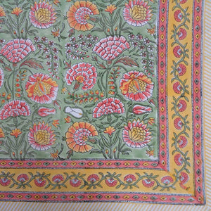 Colorful floral patterned fabric with pink, orange, and yellow flowers on a green background.